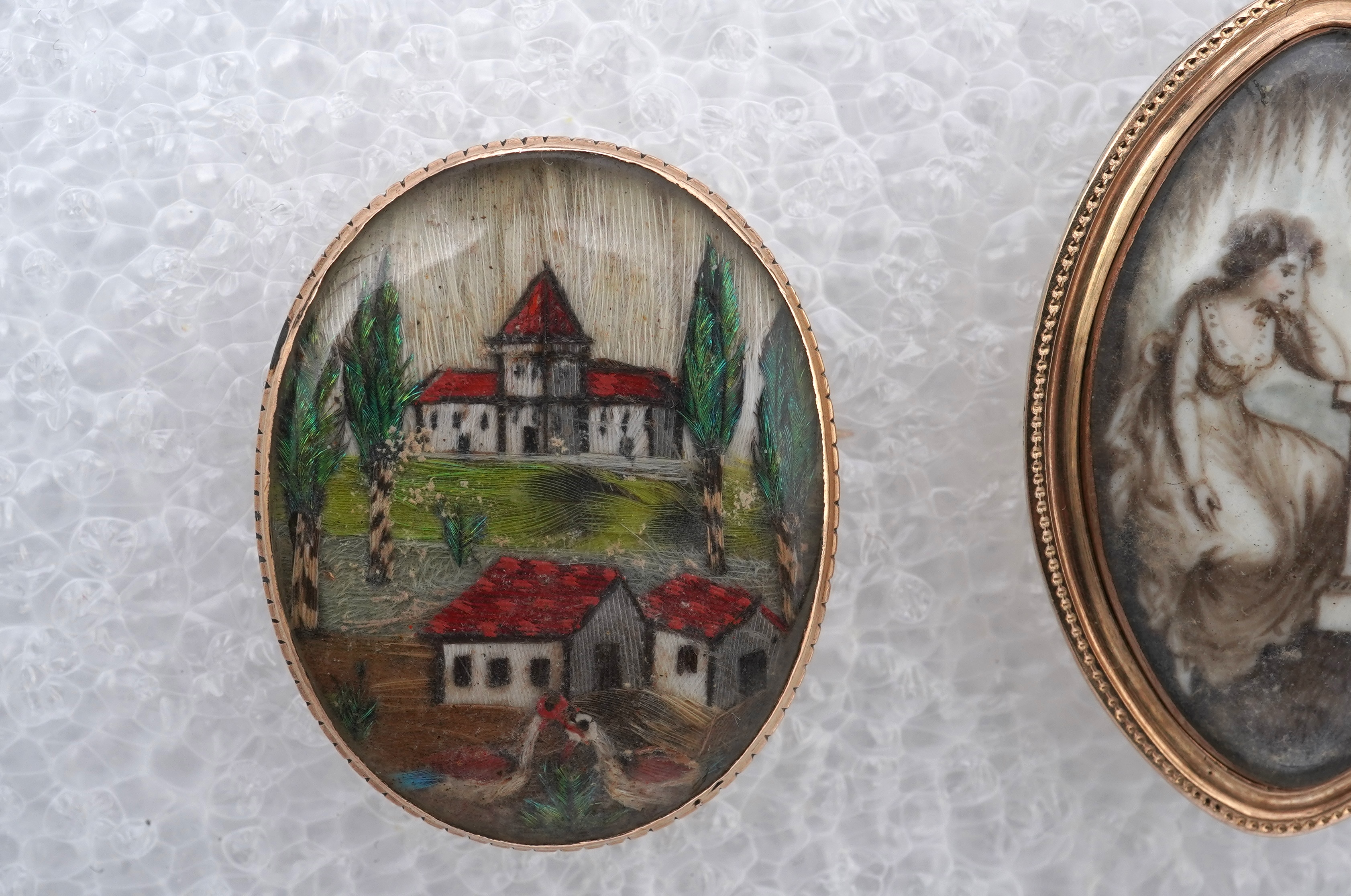 A George III ivory mourning brooch, circa 1786, and a feather work brooch, 19th century